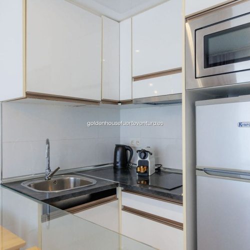 Cocina equipada con un fregadero y una cafetera.