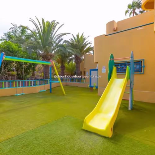Área de recreo infantil con suelo de seguridad azul y estructuras de juego amarillas.