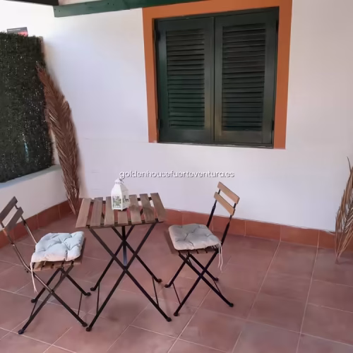 Mesa de madera en patio exterior con decoración de hojas de palmera.