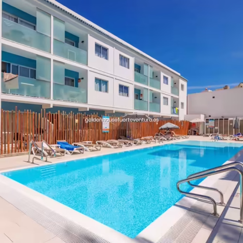 Piscina exterior con hamacas y sombrillas rodeada por la estructura de los apartamentos Bristol Sun Beach.