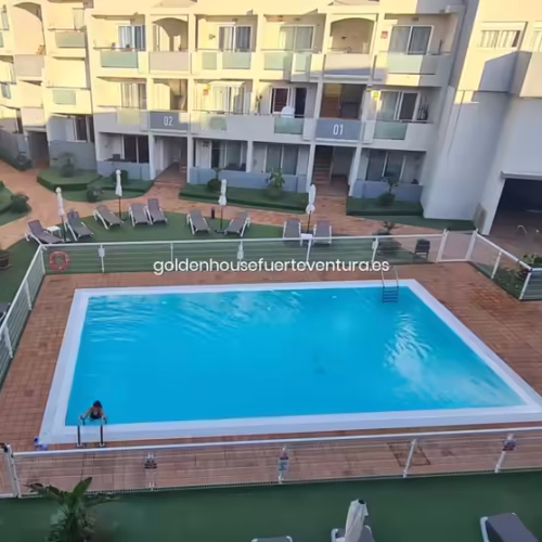 Amplia piscina central con zonas de descanso y balcones del complejo.