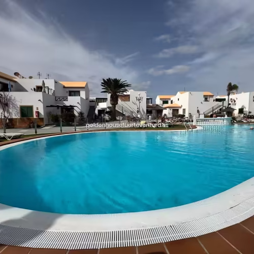 Amplia piscina comunitaria de forma curva bajo un cielo despejado en Fuerteventura.