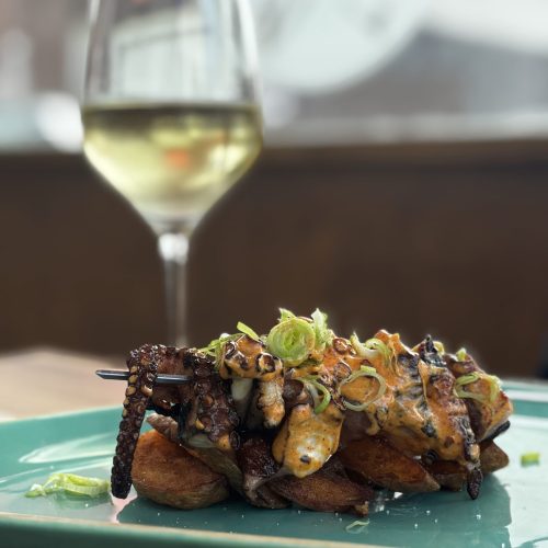 Plato de pulpo a la plancha con papas y vino blanco en La Puipana