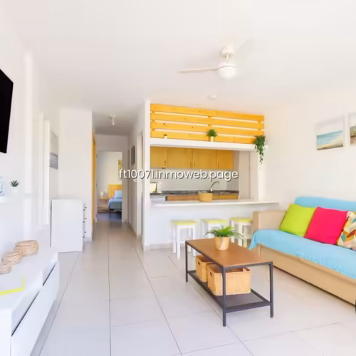 Salón con sofá colorido, televisión y barra de cocina americana