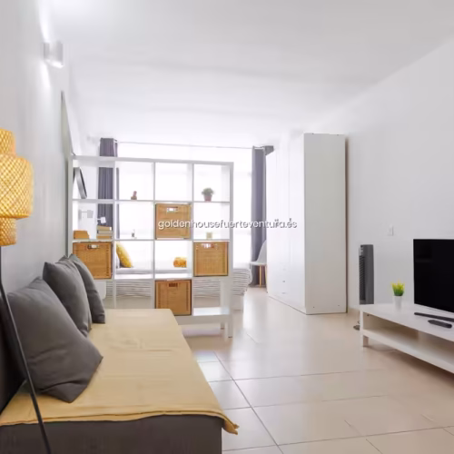 Estantería blanca con cestas de mimbre separando el salón de la zona de descanso