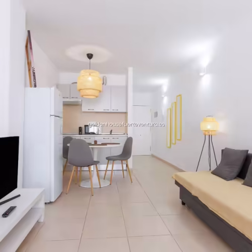Sala de estar con sofá tapizado en ocre, televisión de pantalla plana y lámpara de pie