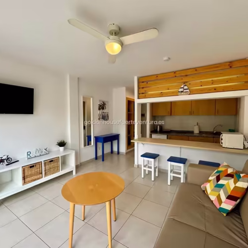 Salón con ventilador de techo y televisor de pantalla plana en Fuerteventura.