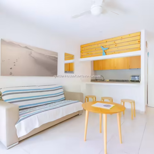 Sofá con funda de rayas azules en un salón blanco con decoración marinera.