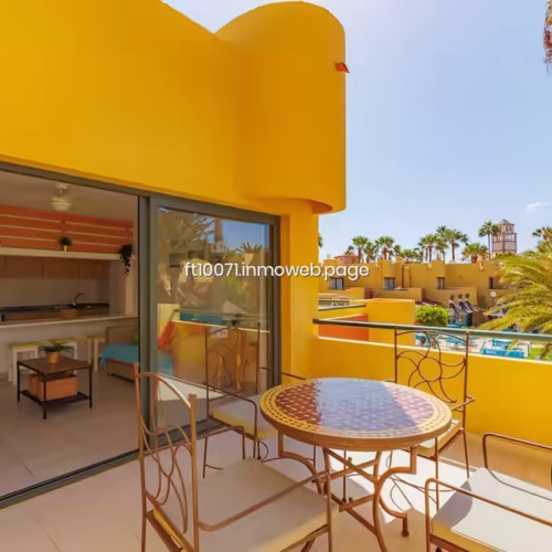 Terraza amueblada con mesa, sillas y vistas al complejo con palmeras