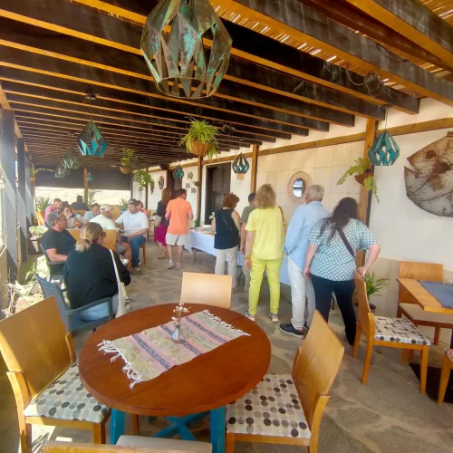 Animado ambiente en la terraza del restaurante Aroma de Sal durante un evento, con clientes disfrutando de un buffet bajo la decoración marinera.
