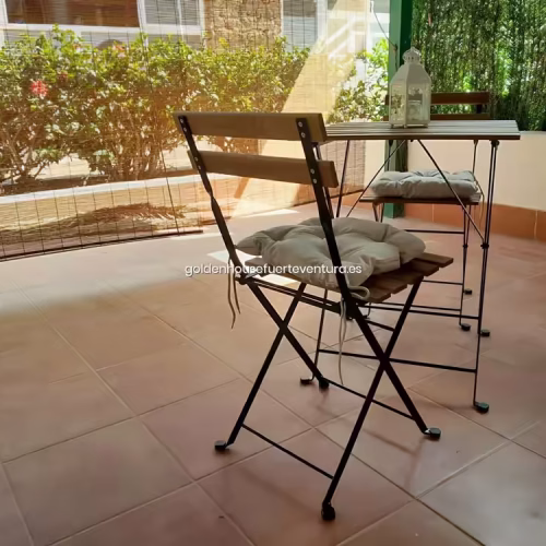 Mesa y sillas plegables con cojines en terraza privada protegida del viento.