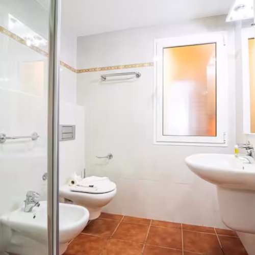 Baño con plato de ducha de cristal, inodoro, bidet y lavabo suspendido en Caleta de Fuste.