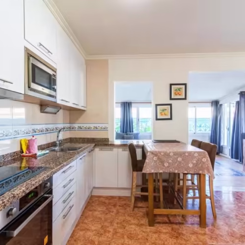Cocina con encimera de granito, vitrocerámica, horno y microondas en Villa Sophia.