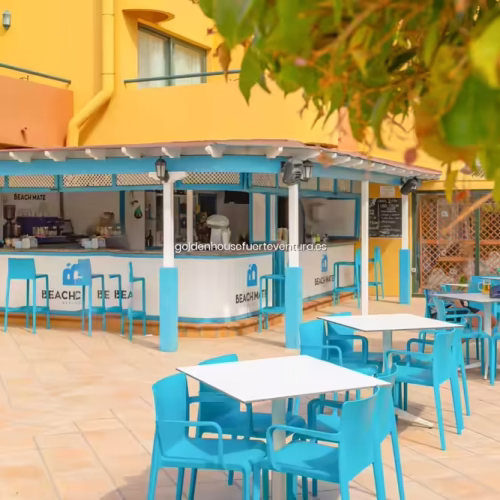 Conjunto de mesas y sillas de bar bajo una estructura techada junto a la piscina.