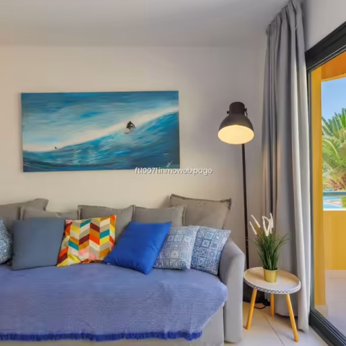 Sofá con cojines de colores y cuadro de temática de surf en la pared.