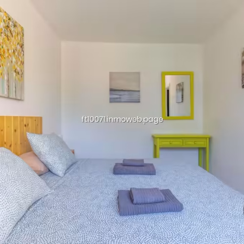 Mesa auxiliar amarilla con espejo en el dormitorio principal
