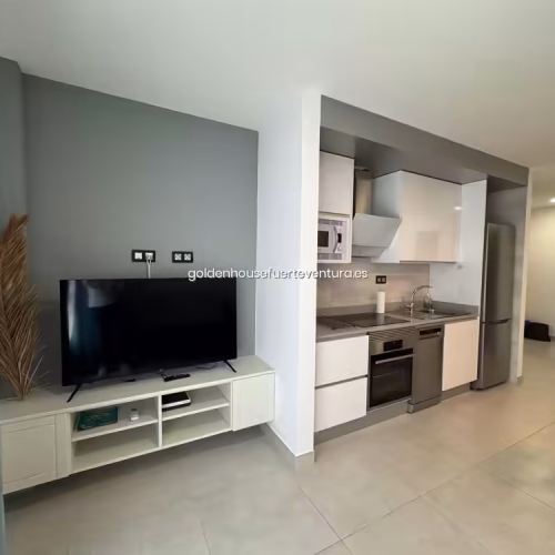 Mueble de televisión blanco con Smart TV sobre pared de color gris.